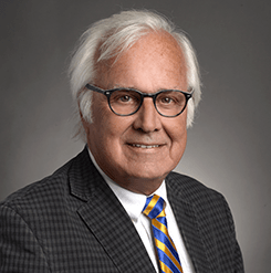 white haired man with glasses wearing a suit