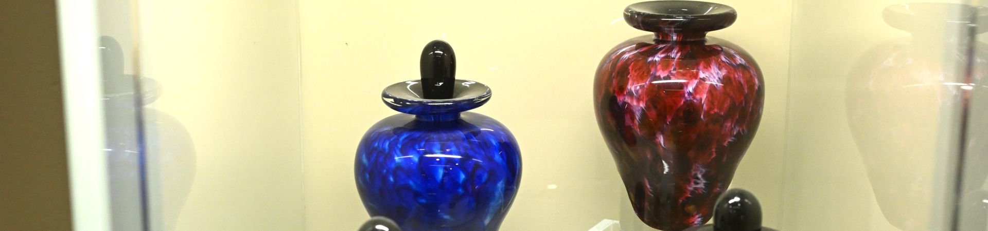 a colourful selection of urns behind a glass display